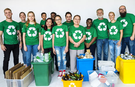 photo of  a group of people standing behind recycled materials