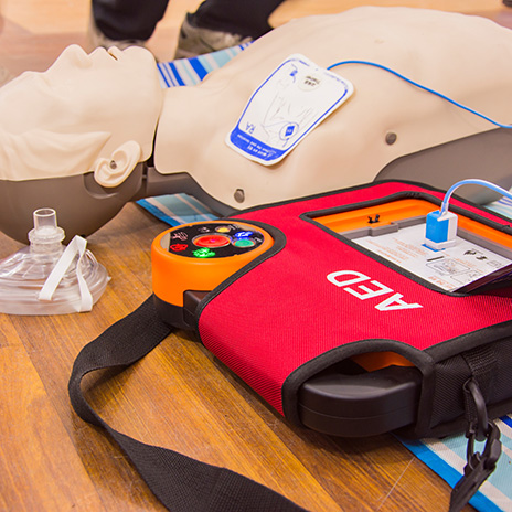 An automated external defibrillator is connected to a mannequin for practice.