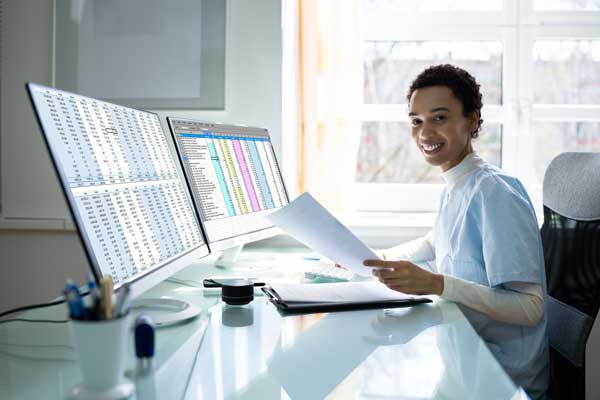 Woman sitting in an office reviewing documents at a computer