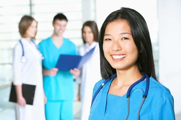 Woman wearing scrubs standing with a medical team