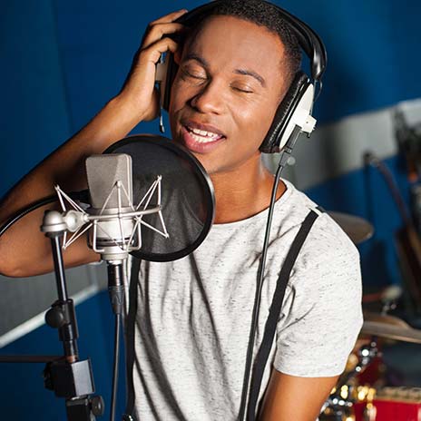 A man sings in front of a microphone in a studio