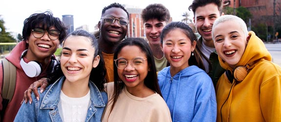 a group of diverse, smiling students standing outside in a city