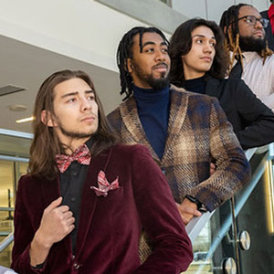 Four Male Achievement Program students in formal attire on an escalator.