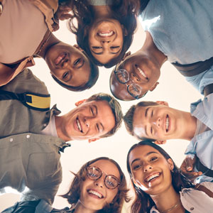 Group of students standing in a circle, looking down at the camera, faces obscured.