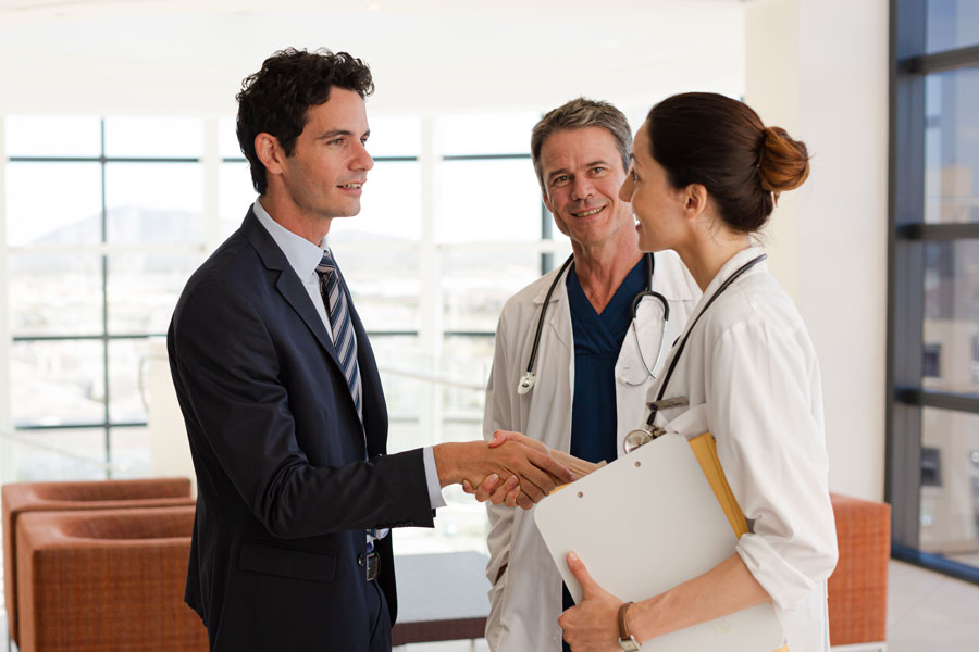 Businessman and two doctors talking and shaking hands