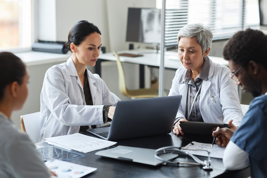 Female clinician in lab coat pointing at laptop screen