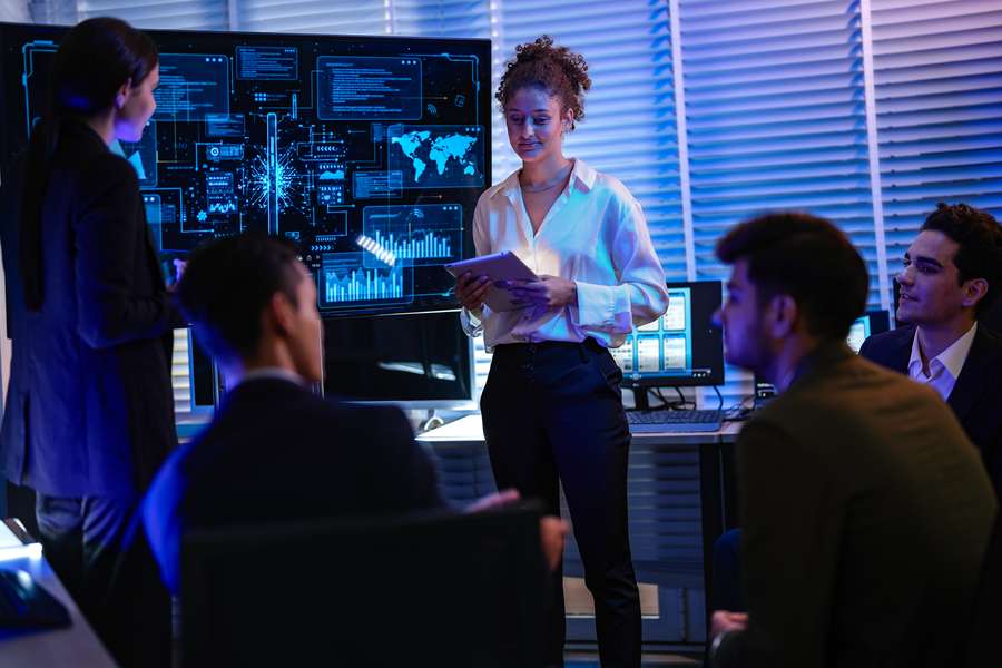female working holding an ipad and standing in front of a group of coworkers