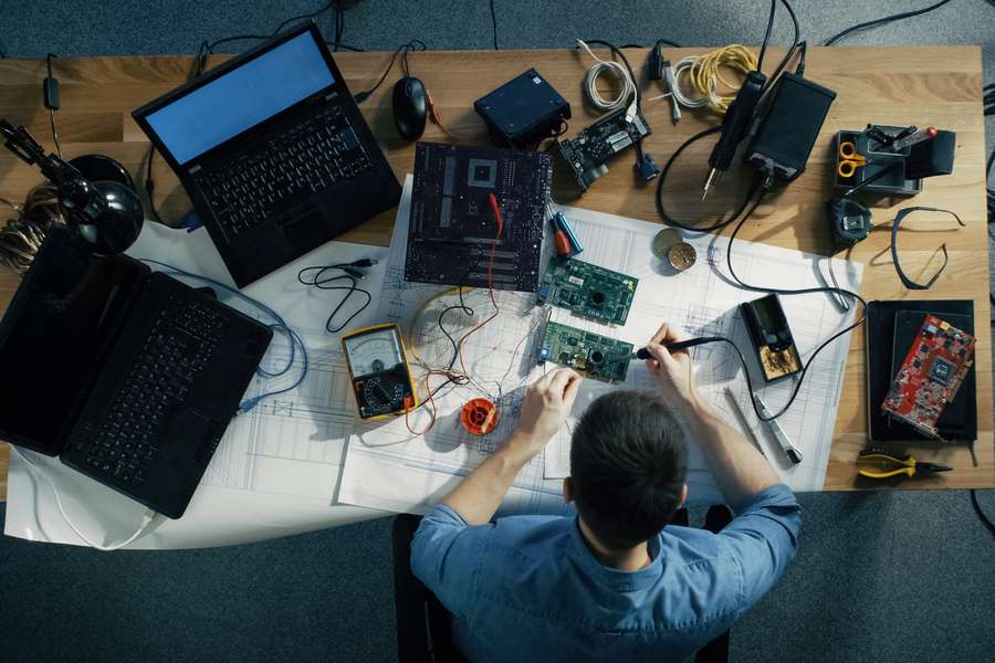 person sitting at a desk with computer hardware pieces