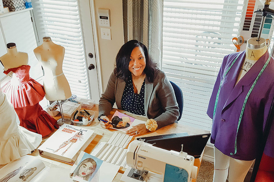 female fashion designing sitting at a table with magazines and a sewing machine