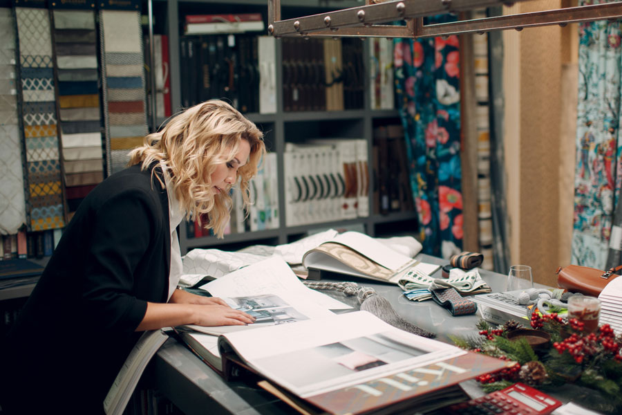 Female Interior designer flipping through a large book with fabrics hanging in the background