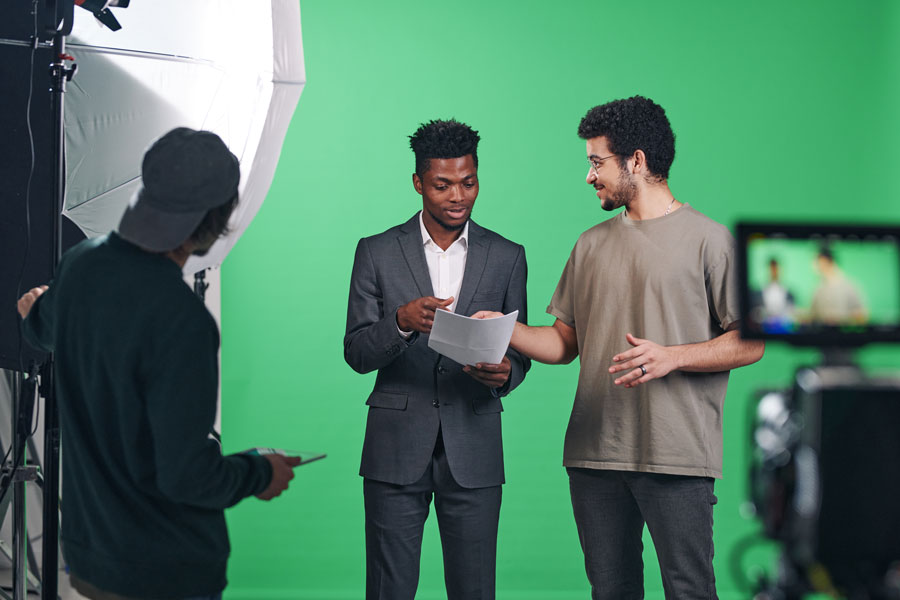 Presenter discussing script with director in front of a green screen