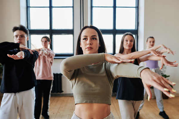 Brunette teenage girl and other teens repeating new dance movements