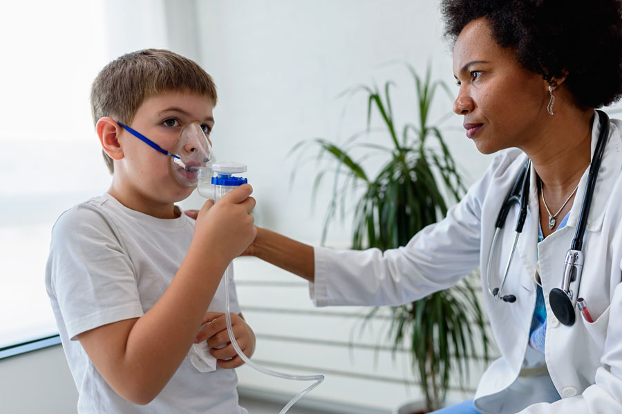 Female doctor helping child use nebulizer inhaler face mask.