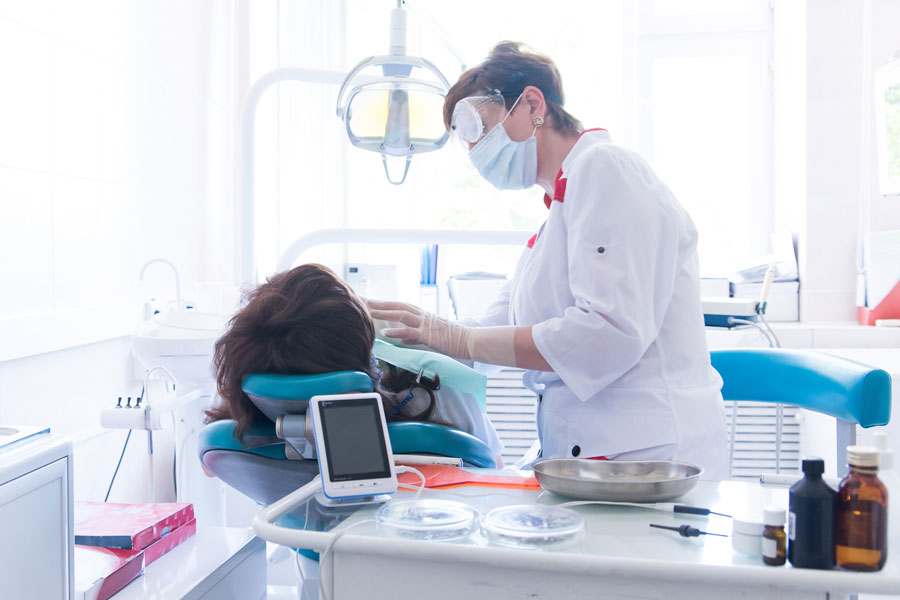 female dental hygienist treats a patient reclining in a chair