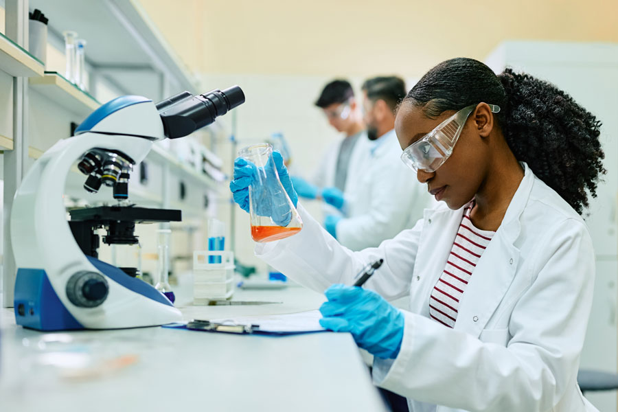Female lab technician analyzing liquid in beaker during her research.