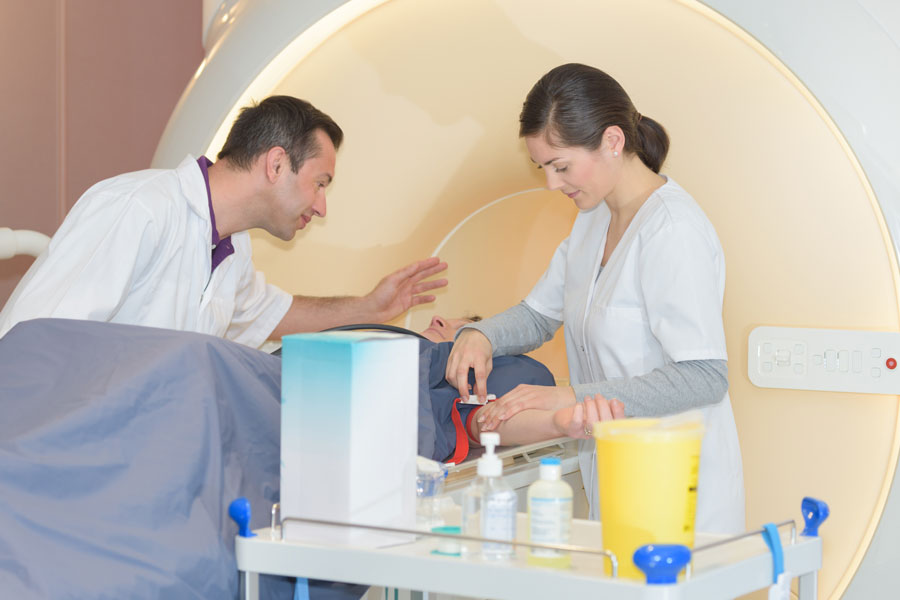 male and female mri specialists prepping a patient lying down in the mri machine