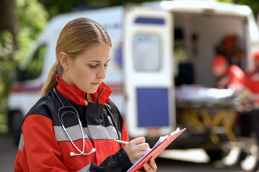 Female paramedic writing notes on medical records