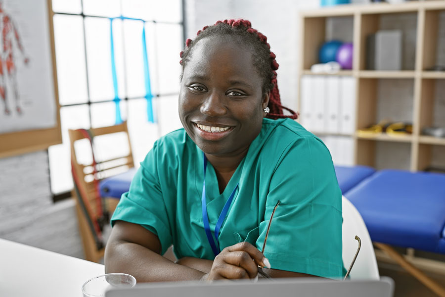 Portrait of a smiling female with braids wearing scrubs in a clinic