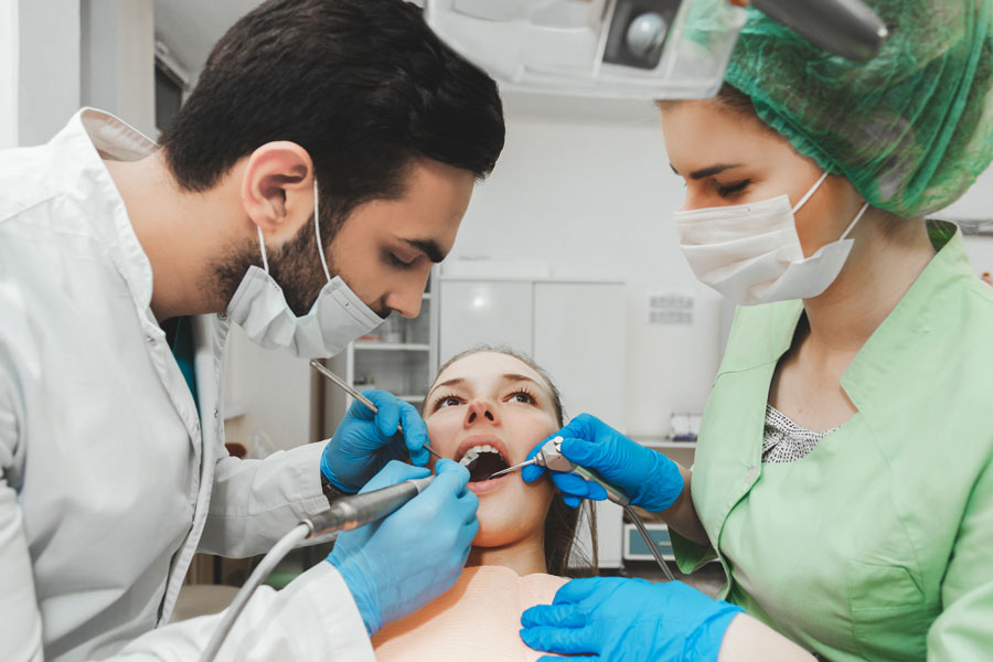 Male dentist and female dental assistant work together to clean teeth