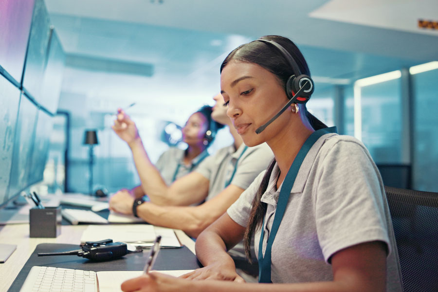 Woman wearing headset sitting at a desk.