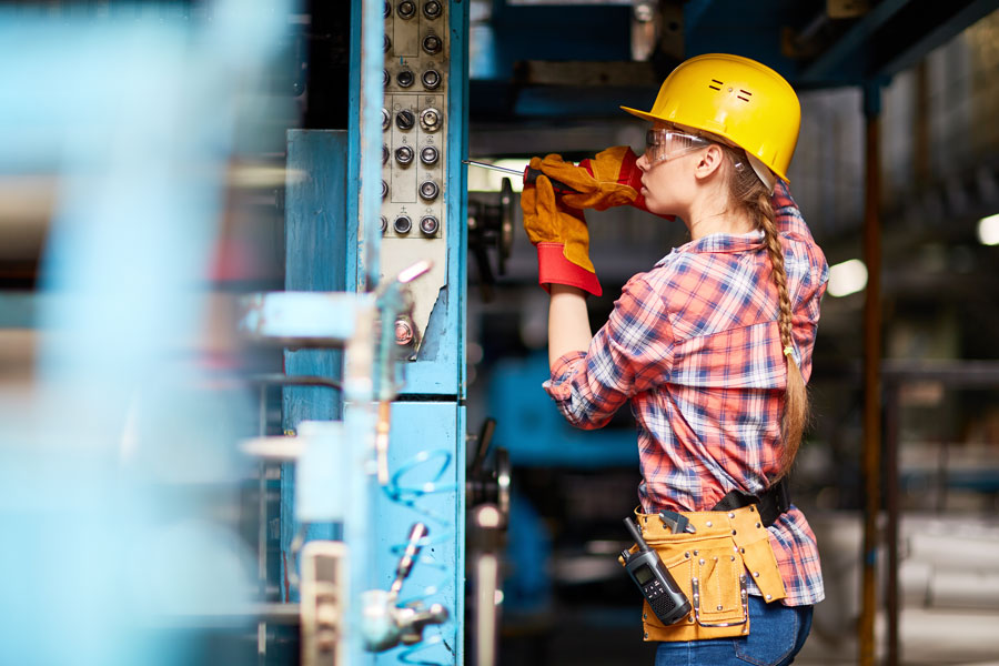 young female electrician wearing yellow construction hat and holding a drill