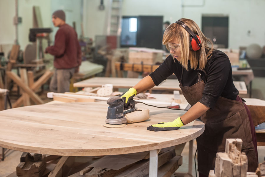 Female carpenter Using Electric Sander for wood