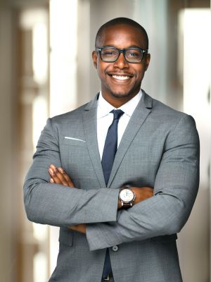 Business Man in a suit stands smiling with his arms crossed