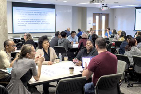 Dallas College employees sit around tables as they take part in a convening session