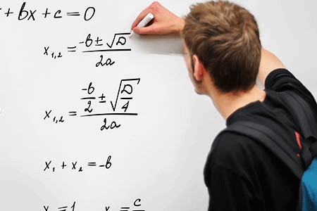 a student writes math equations on a white board