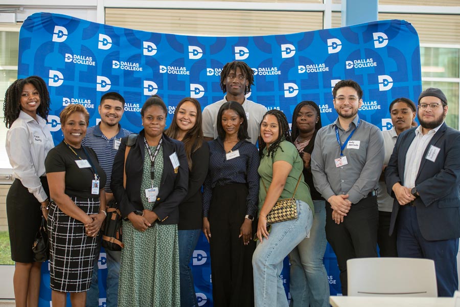 Group of attendees at the Business Tech Symposium 2024 standing in front of a blue Dallas College backdrop
