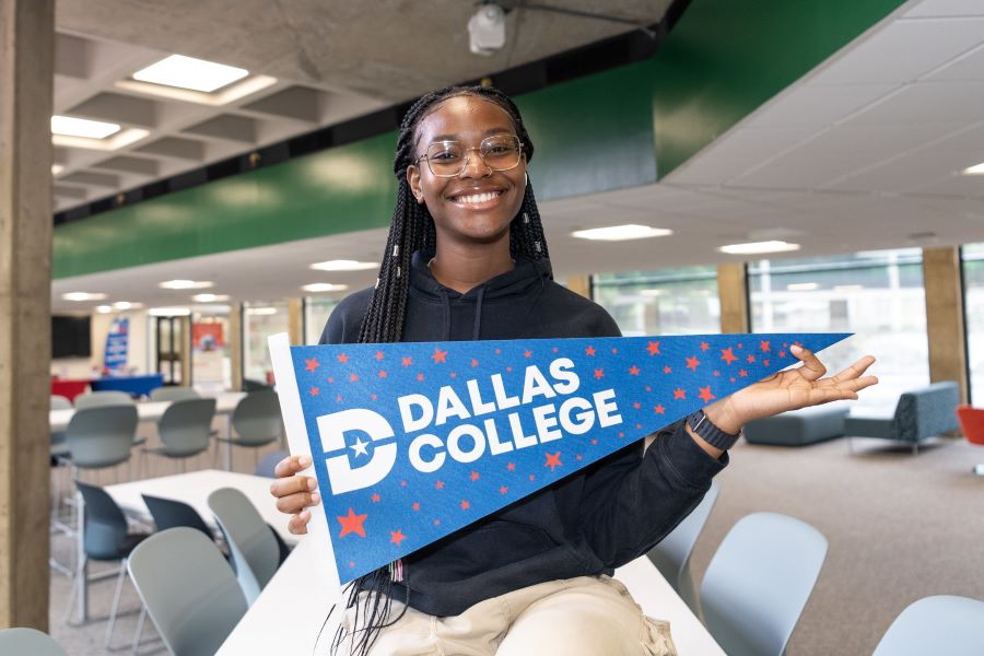 A student holds a Dallas College pennant in the cafeteria at Richland