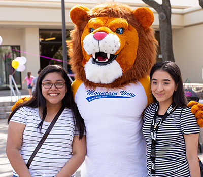 The Mountain View lion mascot stands poses for a photo with two students
