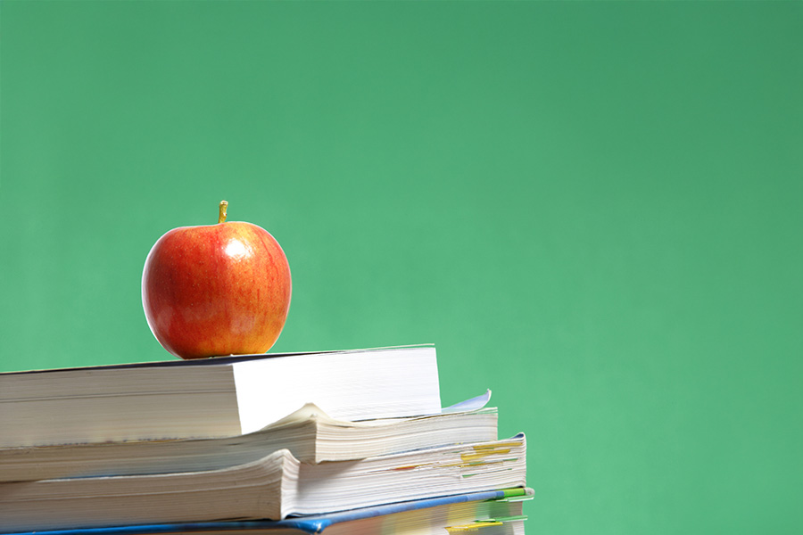 A red apple sitting on top of text books