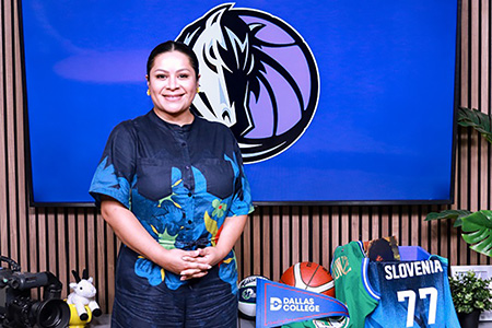 Iris Diaz standing in front of Mavericks logo