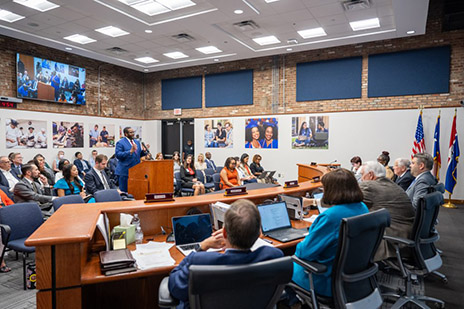 Dr. Tonychris Nnaka at podium addressing board meeting.