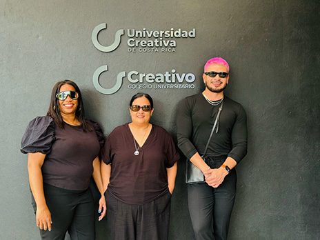 Three Dallas College representatives pose in front of Universidad Creativa sign.