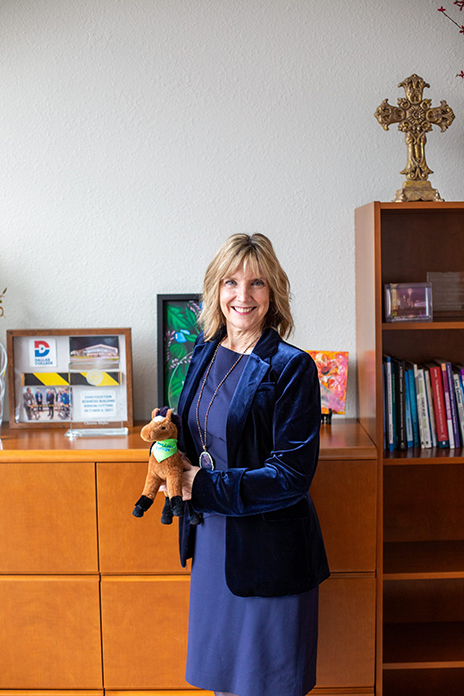 Christa Slejko in her office holding a horse toy