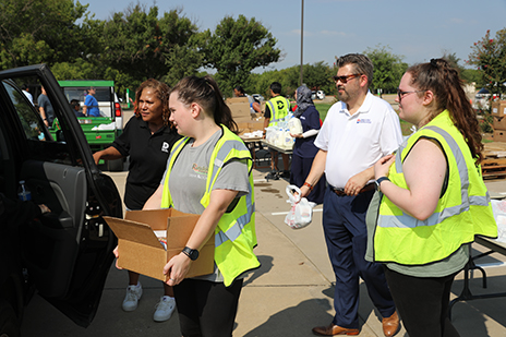 Volunteers, including Dr. Lonon, loading food boxes into a car