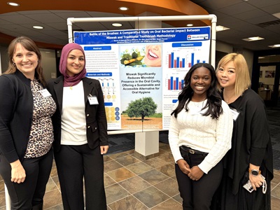 Students and faculty pose in front of large research poster