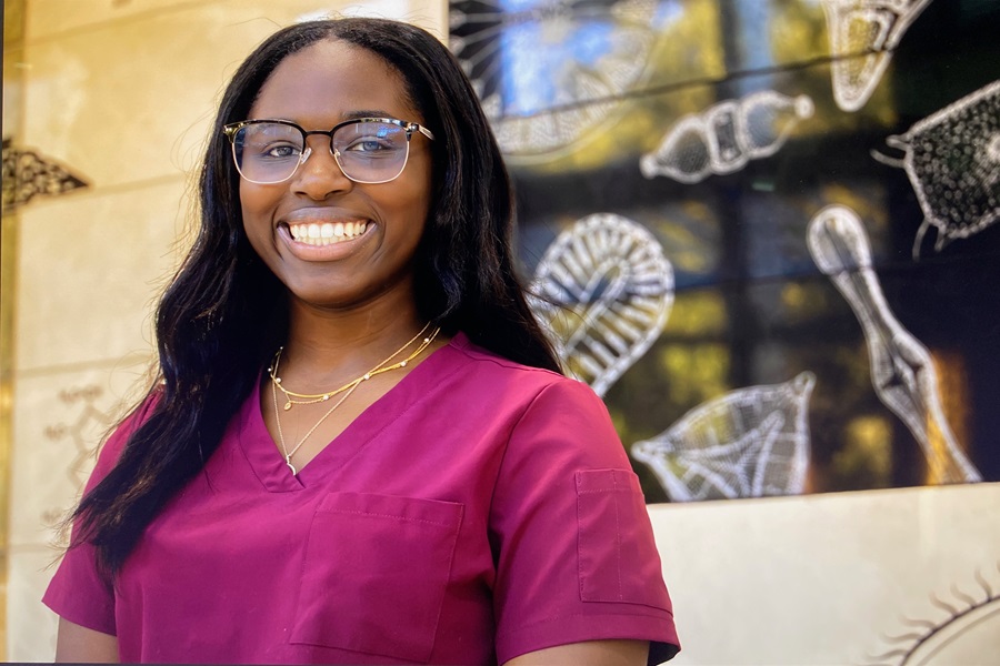 Student poses in front of decorated wall