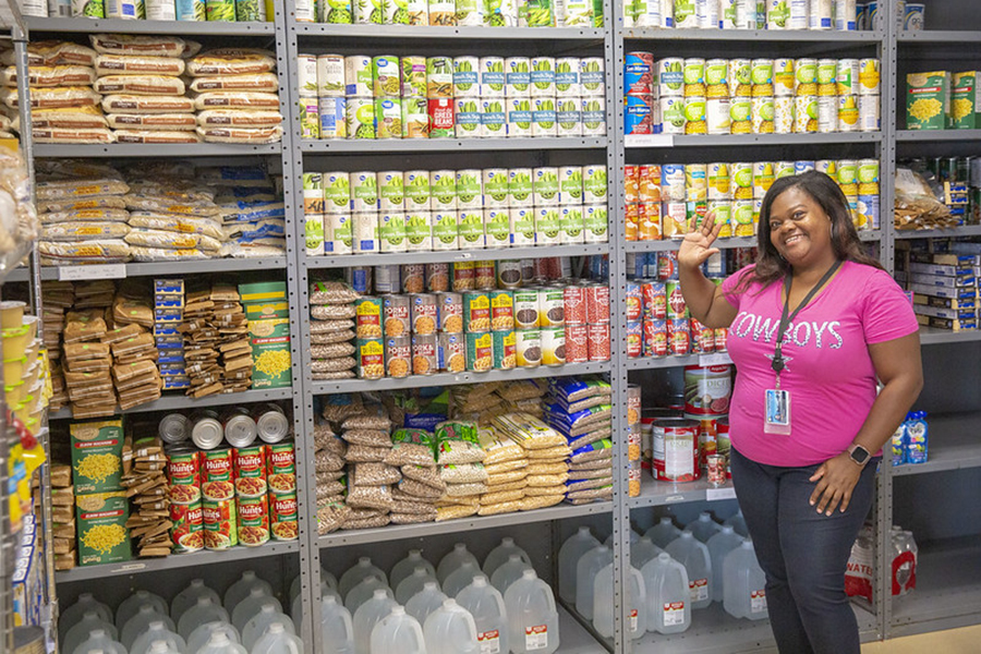 Volunteer standing in front of shelves of food.