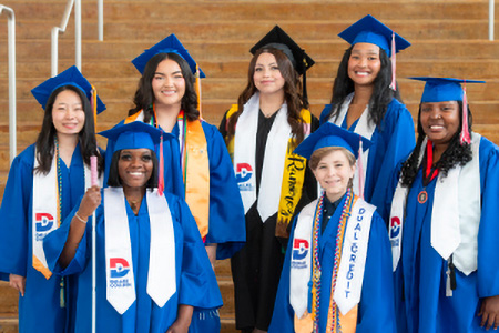 Seven graduation speakers pose for a photo on a set of stairs in their graduation regalia