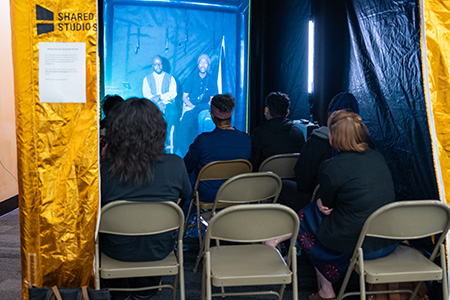 Students sit inside a portal tent facing a screen