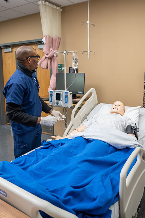 Nursing student adjusting IV on manikin.