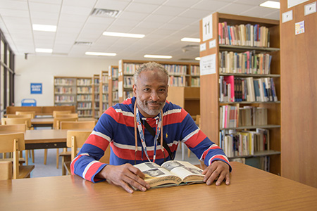 Rod Gordon sits at a table in the library, looking up from a book