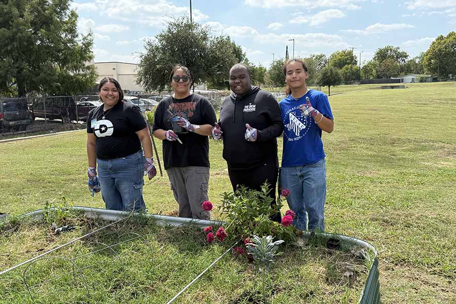 Group of four students standing in front of a raised garden bed
