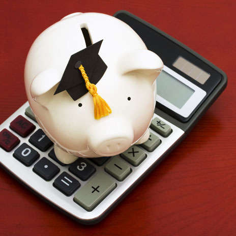 Piggy bank with graduation cap on calculator symbolizing education savings