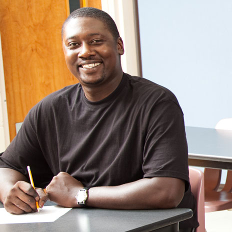 Person wearing a black shirt is writing on paper at a table.