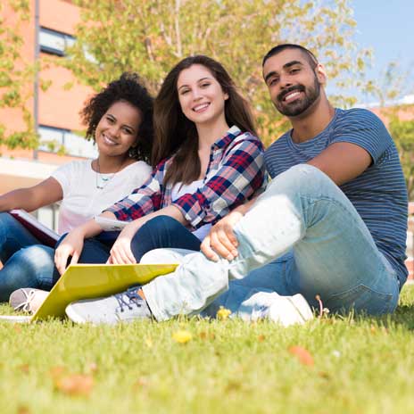 Three students seated on green lawn