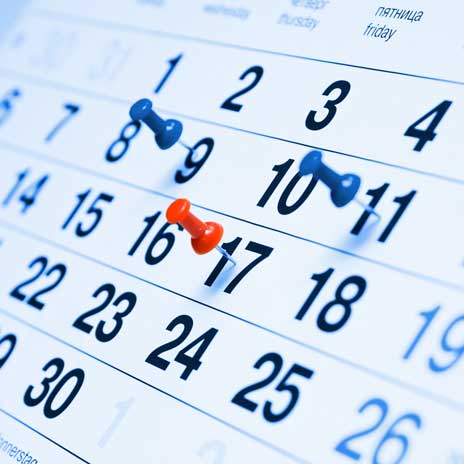 Close-up of a calendar with push pins marking important events or deadlines.